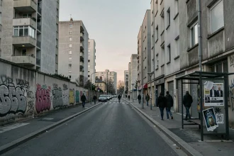 Rue urbaine française au crépuscule avec immeubles en banlieue, graffitis et piétons, illustrant l'insécurité dans les villes françaises